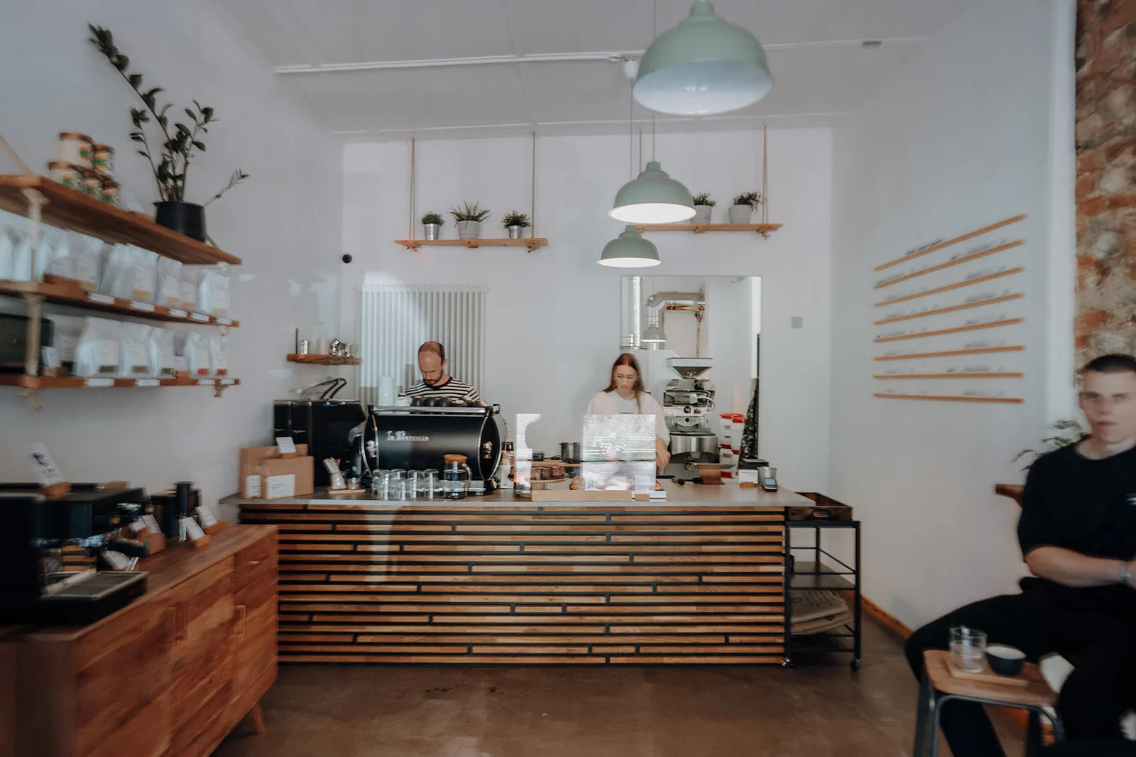 Theke der kofi Kaffeebar mit Siebträgermaschine, Rösterei im Hintergrund und Regalen voller Kaffee