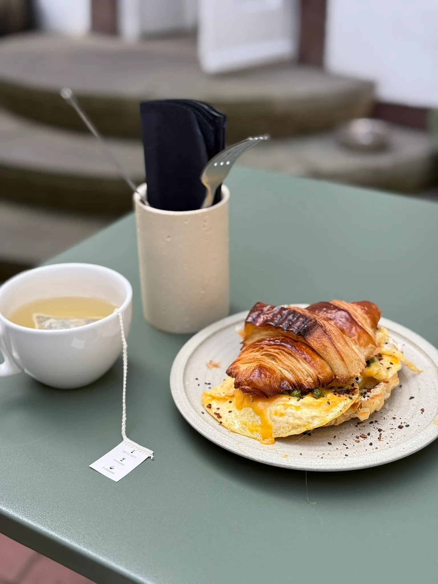 Croissant mit Rührei und eine Tasse Tee auf der Terrasse im Innenhof