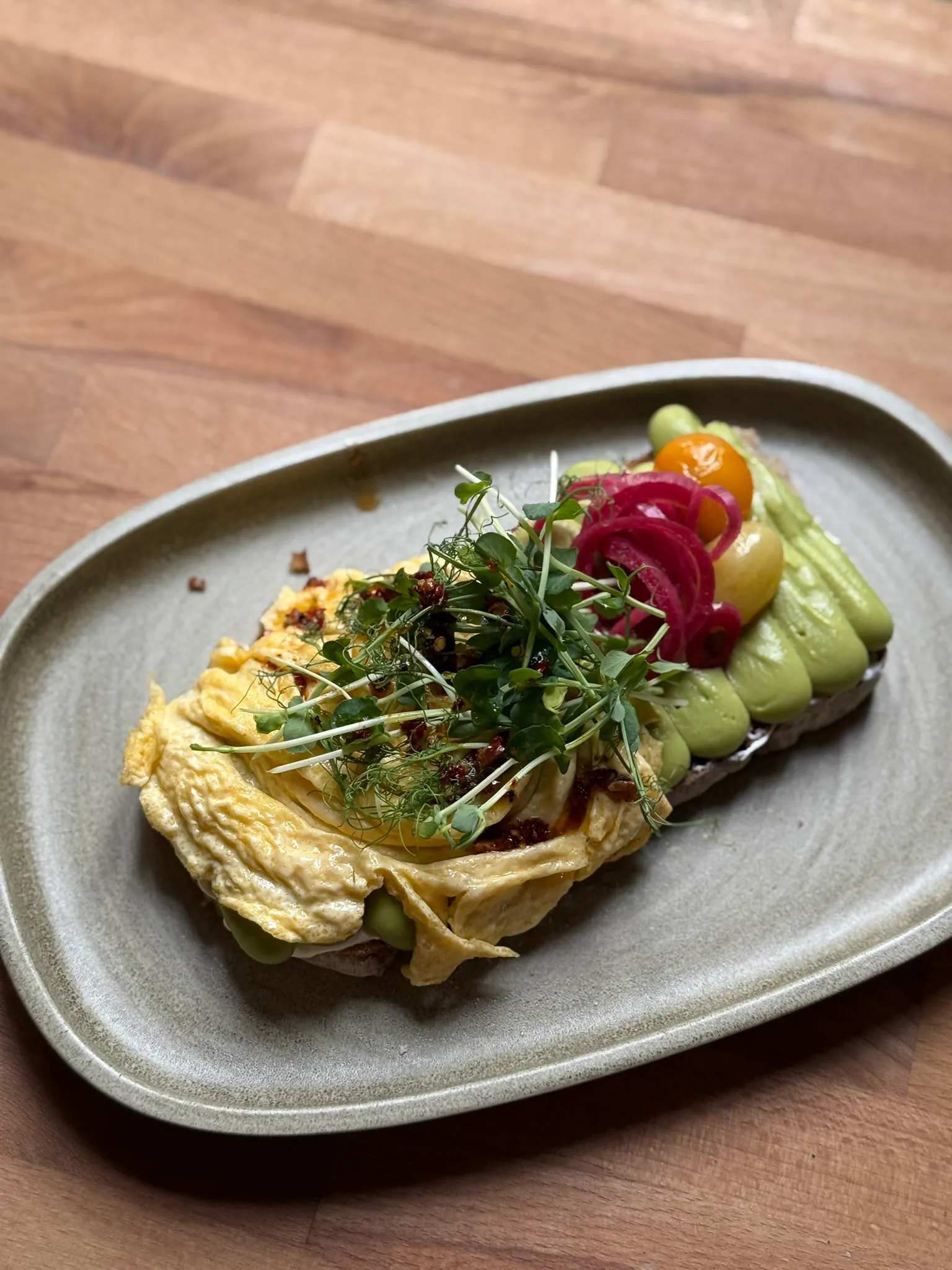 Smashed-Avocado-Stulle mit Rührei, eingelegten Zwiebeln und Microgreens